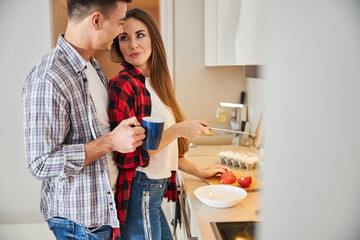 Man with a mug of coffee smiling at his wife