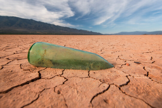aged glass bottle stuck in the mud as a symbol of drought