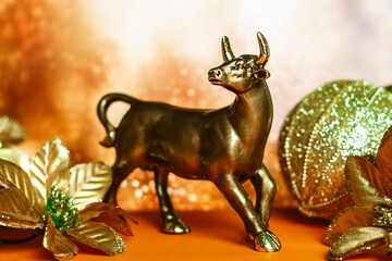 bull as a symbol of the coming year 2021 according to the Chinese calendar, poinsettia and a bag of gifts in gold colors