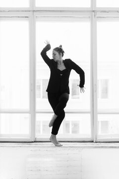 dancing barefooted girl with a back leaned to the window