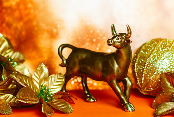 bull as a symbol of the coming year 2021 according to the Chinese calendar, poinsettia and a bag of gifts in gold colors
