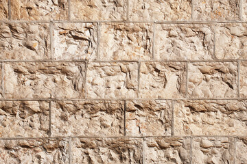 Brown brick wall. Horizontal decorative uneven blocks background. Urban architecture texture. Solid stone texture. Grunge brickwork structure.