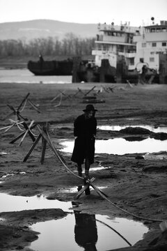 Black and white portraits of a young woman against large sea vessel on the dry riverbed