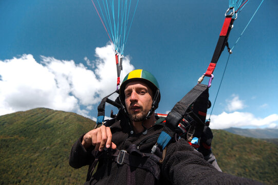 Man taking selfie while paragliding high in green mountains