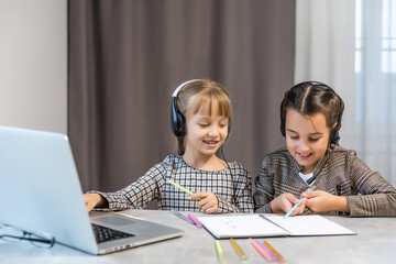 Education at home concept - two Cute little playful girls studying doing homework on laptop