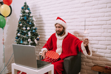 Santa Claus video calling kid talking to kid, Merry Christmas, Happy New Year in virtual video online chat meeting on laptop sitting at workshop table sending gift on xmas eve. Gift and sparkles