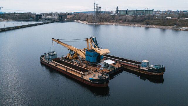Floating crane at work. Loading empty cargos in the sea.