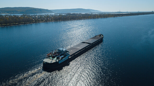 Top-view of a cargo ship in the canal with a mountain chain at background