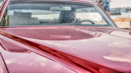 portrait of young adult beautiful afro american woman sitting inside red retro vintage car African girl hold in hand full bottle of cola with plastic tube Female with smiley face look at far away
