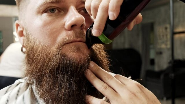 Barber cuts the client's mustache and beard, combs his hair. Trendy beard trim, takes care of themselves.