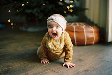 little girl crawling away from the christmas tree in a hurry
