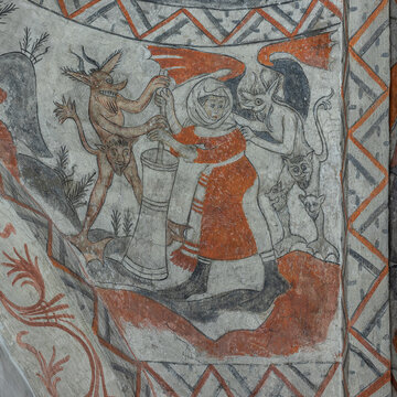 Medieval fresco of a woman churning butter with two ugly devils