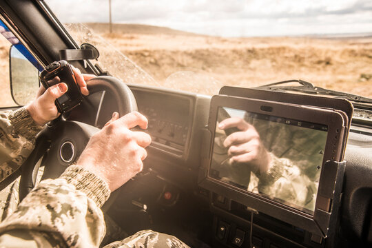 No face Unrecognizable person man holding mobile phone with gps application in the car with tablet screen computer Sun light  on finger Sunset rays on hands Soldier male inside brutal SUV car
