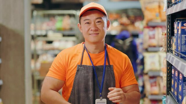 Asian young man sales consultant working at supermarket crossing arms confident posing for camera. Professional employee. Supermarket worker.
