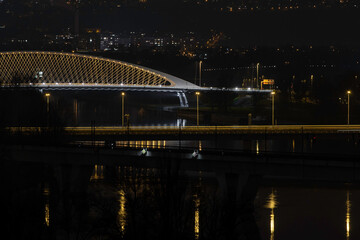 
view of street lighting on bridges on the Vltava river in the city of Prague at night and lights from passing cars