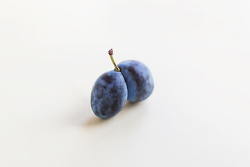 Ugly organic blue double plums heart-shaped on a white background. The ugly produce trend is the sale of imperfect-looking produce.