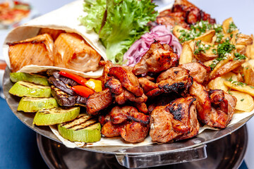 Mixed grill meat fried vegetables and grilled salmon fish fillets decoration in warm dish. Assorted delicious grilled kebab served with herbs on platter. Restaurant menu barbecue plate Bbq party meal