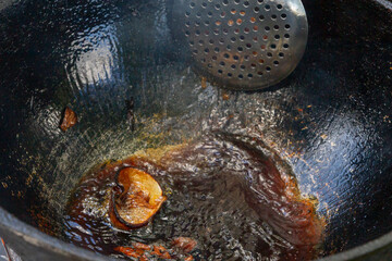 Cooking pilaf in a cauldron on the grill outside in the summer