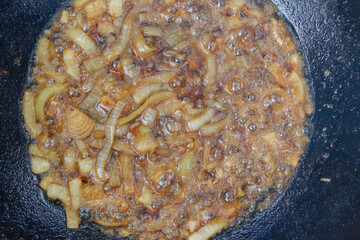 Cooking pilaf in a cauldron on the grill outside in the summer