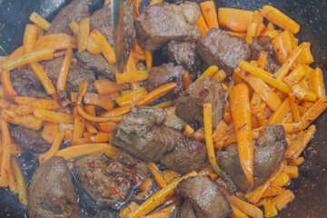 Cooking pilaf in a cauldron on the grill outside in the summer