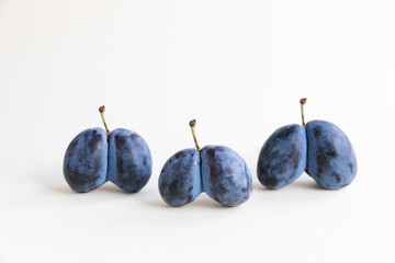 Ugly organic blue double plums heart-shaped on a white background. The ugly produce trend is the...