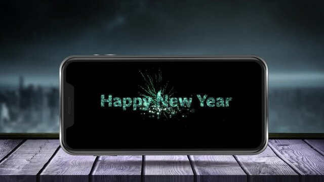 Animation of fireworks exploding and happy new year text displayed on smartphone screen with winter 