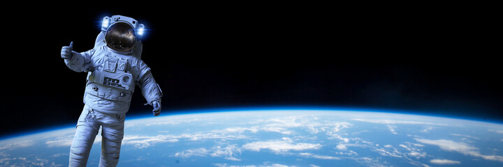 astronaut during a spacewalk in orbit of planet Earth, background banner format