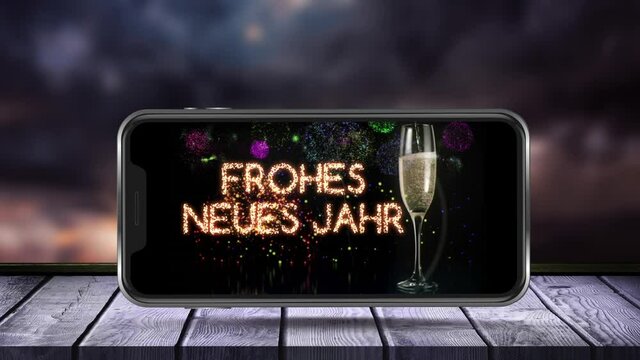 Animation of frohes neues jahr text and glass of champagne on smartphone screen and fireworks