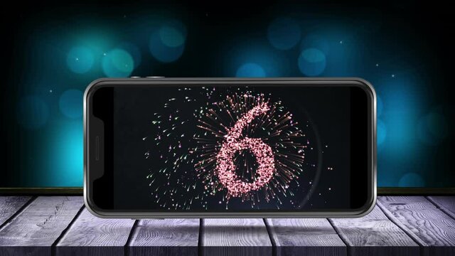 Animation of fireworks exploding with glowing countdown to midnight displayed on smartphone screen o