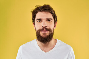 Obraz premium A man in a white t-shirt gestures with his hands lifestyle cropped view yellow background more fun