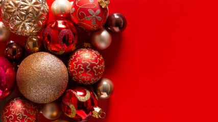 Banner with red background and red and gold Christmas balls, decoration on the left. Christmas card. Texture and pattern. Flat lay, top view, copy space. New year concept. Winter holidays