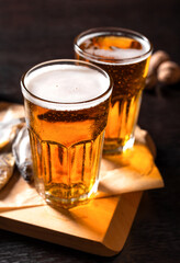 Close up. Two glasses of cold beer and snacks on a wooden table on a dark background. Dried fish and nuts. Fast food in local brewery, pub, bar. Oktoberfest. Still life, rustic