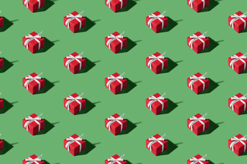 Christmas isometric pattern, background, banner. Minimal composition made of Christmas red gift box on a green background. Top view. Holiday New Year concept. Xmas presents, congratulations