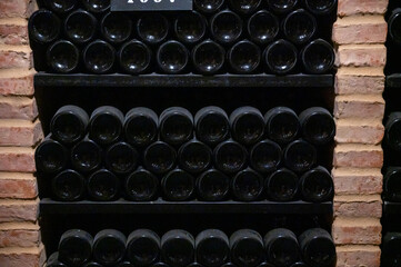 Fototapeta na wymiar Bottles of vintage fortified ruby or tawny porto wine in old cellars of Vila Nova de Gaia, Portugal
