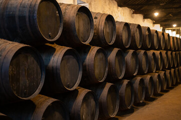 Old porto lodge with rows of oak wooden casks for slow aging of fortified ruby or tawny porto wine in Vila Nova de Gaia, Portugal