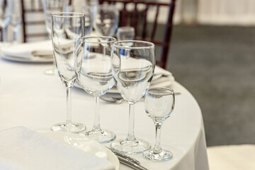 Fancy table set for dinner with napkin glasses in restaurant, luxury interior background. Wedding elegant banquet decoration and items for food arranged by catering service on white tablecloth table.
