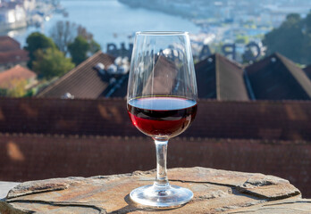 Tasting of different fortified dessert ruby, tawny port wines in glasses with view on Douro river, porto lodges of Vila Nova de Gaia and city of Porto, Portugal