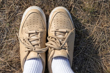 Nude leather shoes and  white high socks with dry grass background