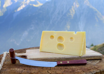 Cheese collection, French emmental de savoie cheese with round holes served outdoor in Savoy region, with Alpine mountains peaks on background