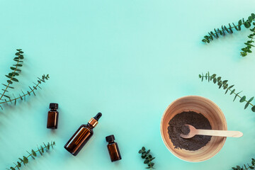 Natural organic cosmetics: clay, cosmetic oil, essential oils and eucalyptus on blue background. Top view, flat lay
