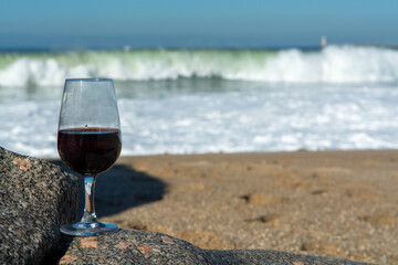 Tasting of different fortified dessert ruby, tawny port wines in glasses on sandy beach with view on waves of Atlantic ocean near Vila Nova de Gaia and city of Porto, Portugal