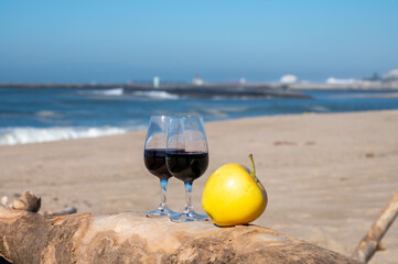 Tasting of different fortified dessert ruby, tawny port wines in glasses on sandy beach with view on waves of Atlantic ocean near Vila Nova de Gaia and city of Porto, Portugal