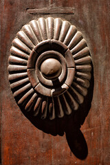 Detail of an ornate carved surround for a doorbell on a timber door