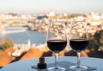 Tasting of different fortified dessert ruby, tawny port wines in glasses with view on Douro river, porto lodges of Vila Nova de Gaia and city of Porto, Portugal