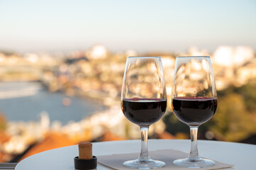 Tasting of different fortified dessert ruby, tawny port wines in glasses with view on Douro river, porto lodges of Vila Nova de Gaia and city of Porto, Portugal