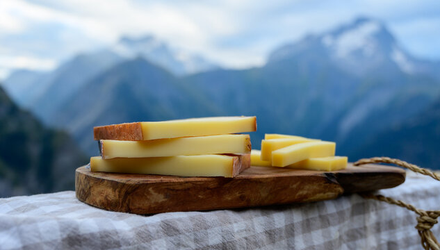 Cheese collection, French comte, beaufort or abondance cow milk cheese served outdoor with Alps mountains peaks on background