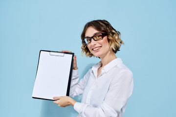 Business woman with documents in a folder on a blue background and in a light shirt glasses on her face