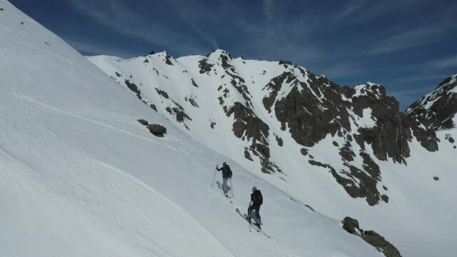 Aerial footage of two ski mountaineers ascending on a snowy ridge