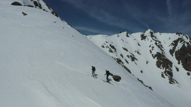 Two Ski Mountaineers ascending steep alpine terrain on snowy ridge
