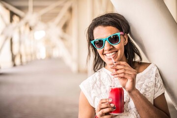 outdoor portrait of Teenage african girl drink cool drinks from metal red can with plastic tube...